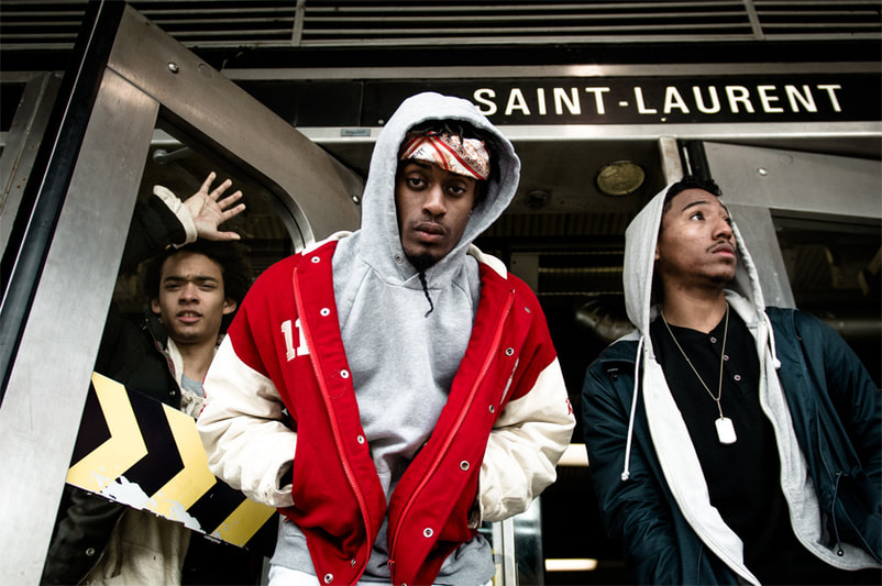 Hands in pocket with varsity and bomber jackets, the dark skinned trio poses in front of St Laurent station in Montreal. © The National Music Centre